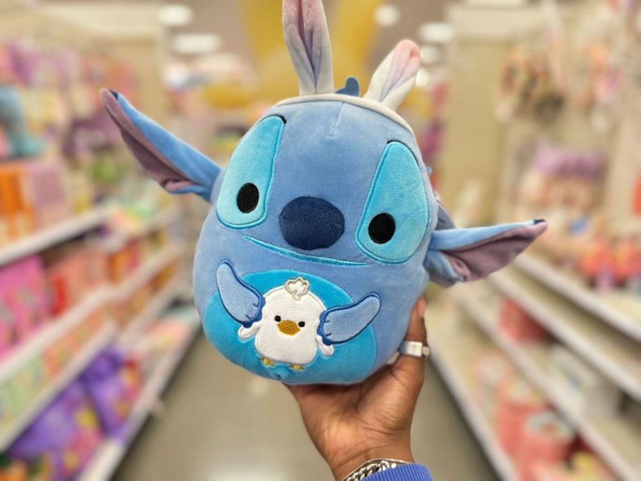 A person holding a Squishmallows Easter Disney Stitch in Bunny Suit