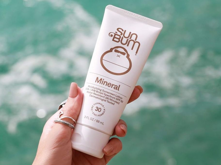 Hand holding a tube of Sun Bum Mineral Sunscreen SPF 30