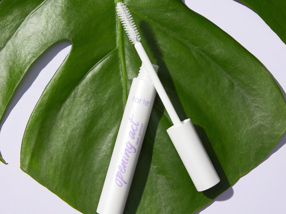 opened white tube of Tarte Opening Act Lash Primer on a green leaf