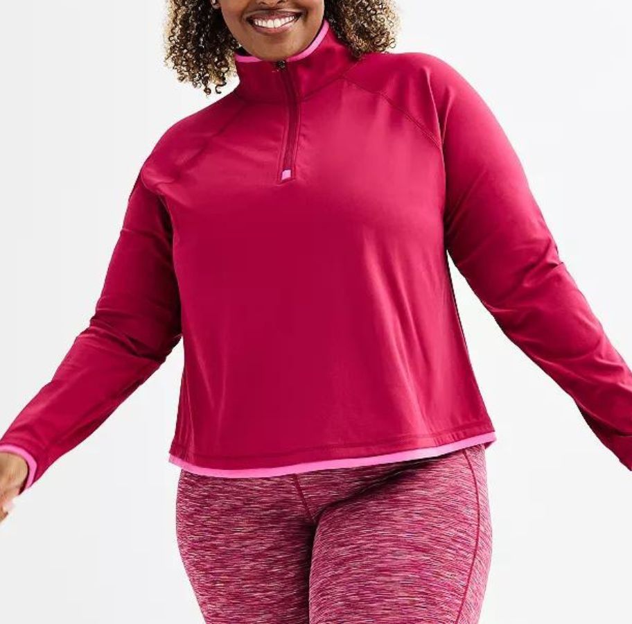 A woman wearing a pink Tek Gear Plus Sized Color Blocked Quarter Zip Pullover