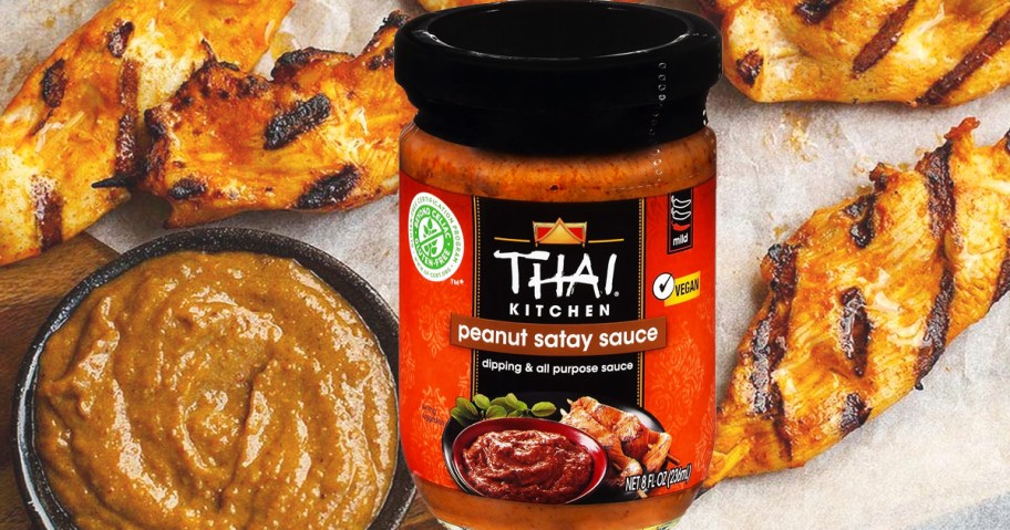 jar of Thai Kitchen Peanut Satay Sauce in front of grilled chicken skewers