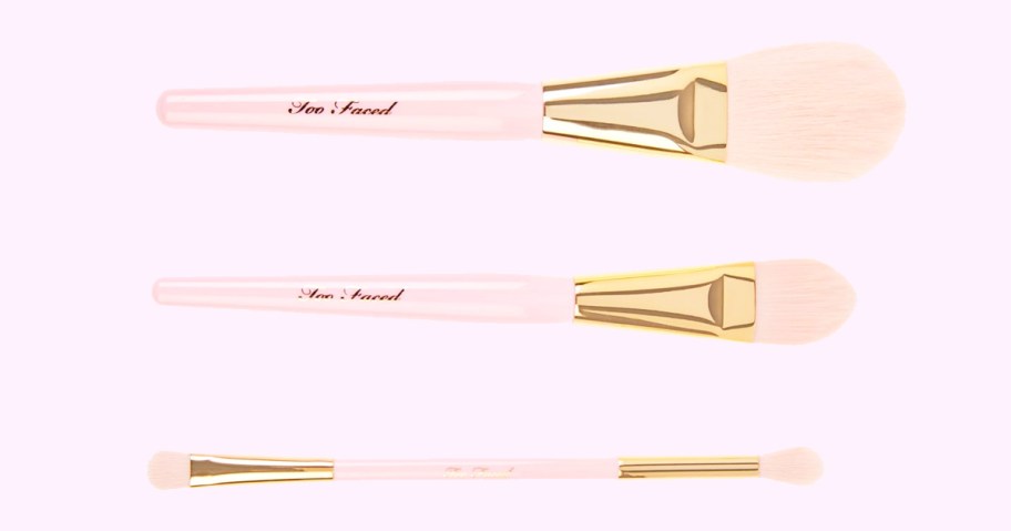 three gold and pink makeup brushes