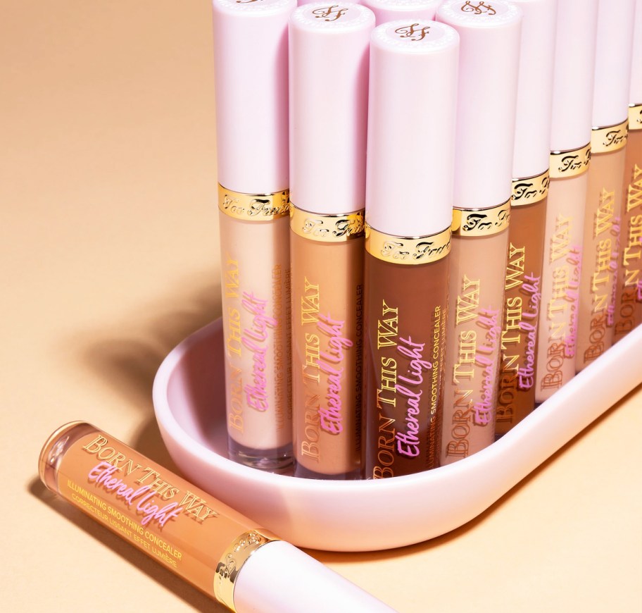 multiple tubes of Too Faced Born This Way Ethereal Light Smoothing Concealer in various shades on a pink tray