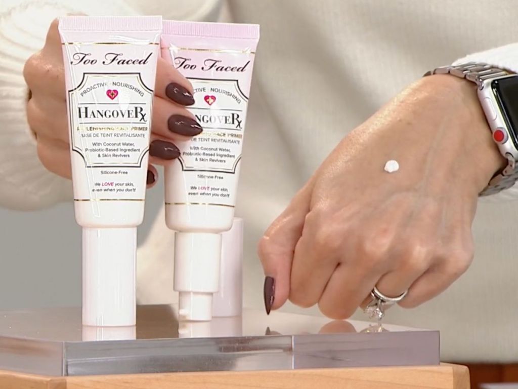 2 tubes of Too Faced Hangover Primer with a dot of it on a woman's hand next to them