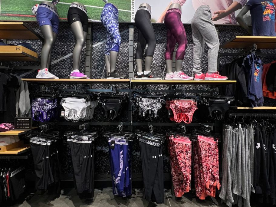 A wall of Under Armour Girls Leggings and Sports Bras