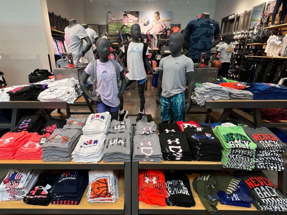 A display table of Under Armour Kids Tees