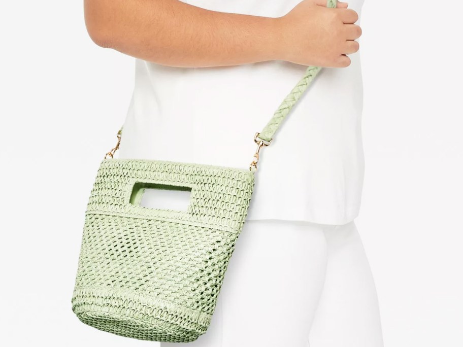 woman in white outfit with light green straw crossbody bag