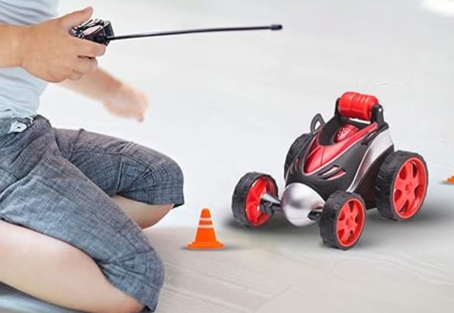 little boy playing with a red and black RC stunt car