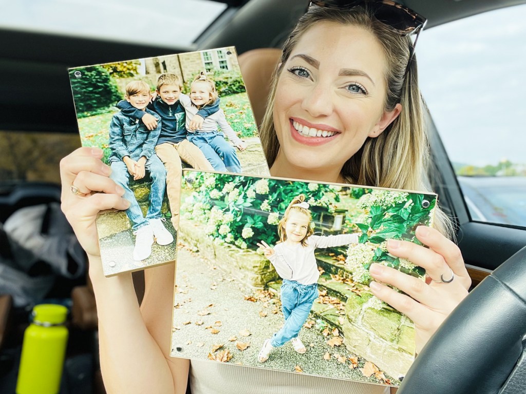 woman holding up two wood panel prints in car