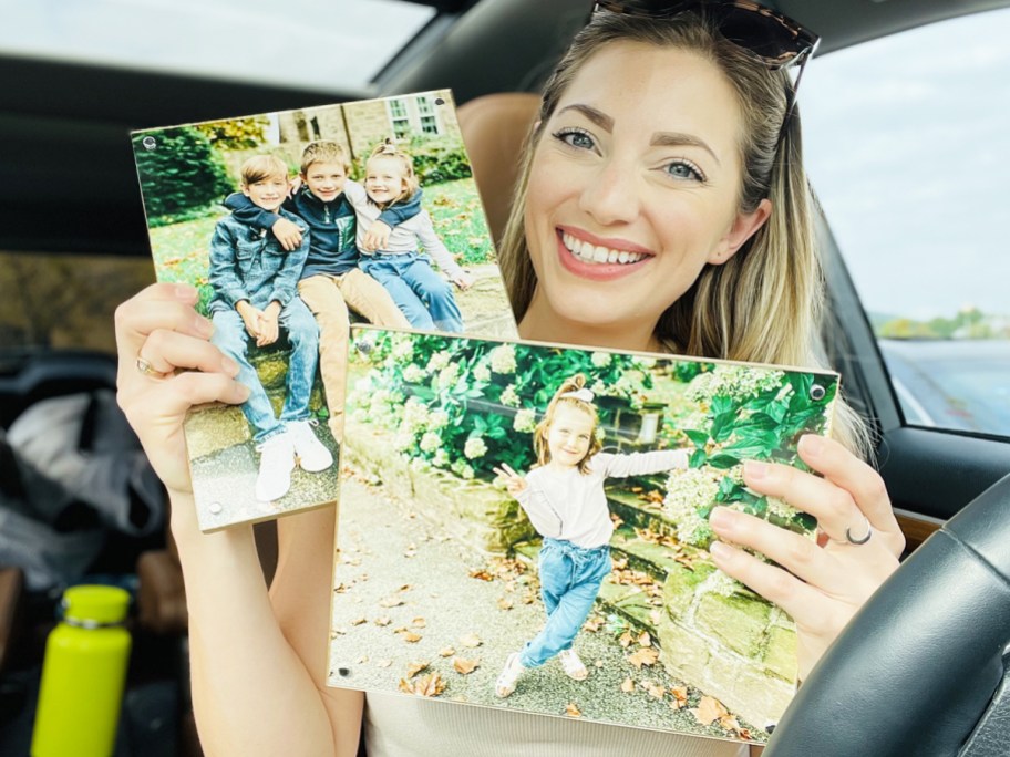 woman holding up two wood panel prints in car