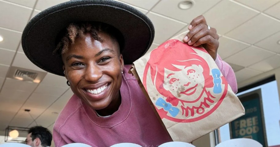 woman wearing hat and holding up Wendy's bag