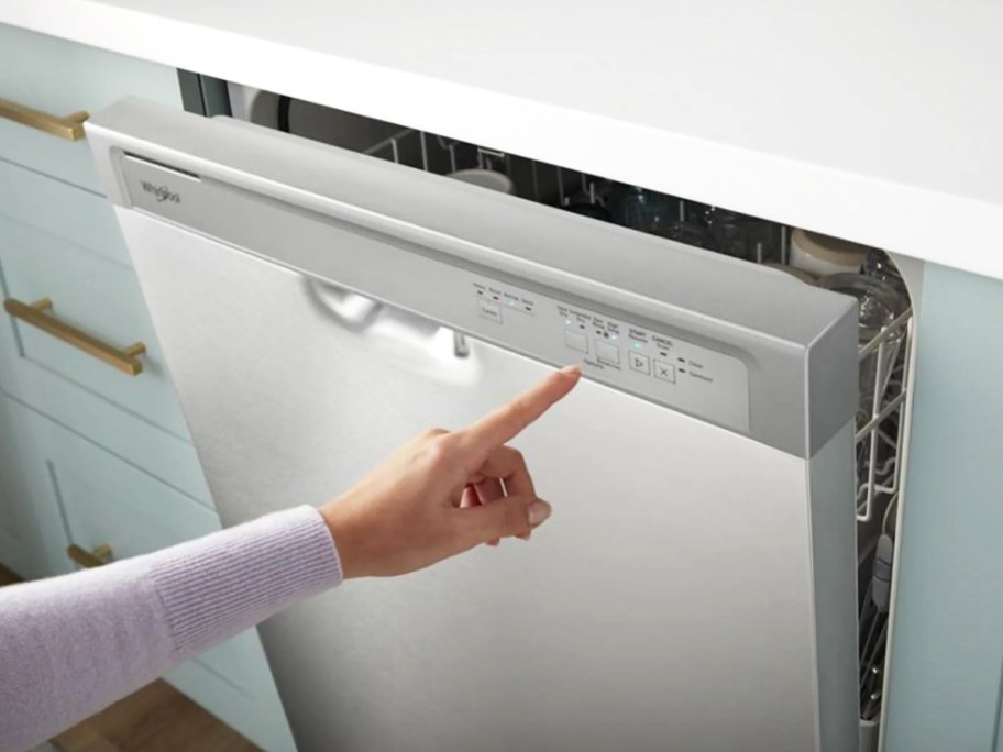 woman pushing buttons on front of white dishwasher