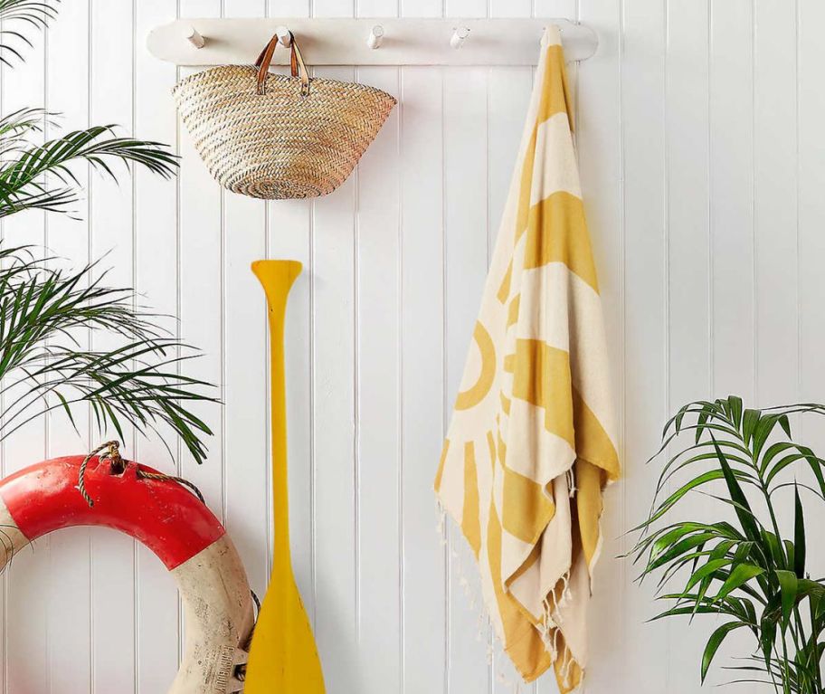 A yellow Whitley Willows towel hanging on a peg on a wall. 