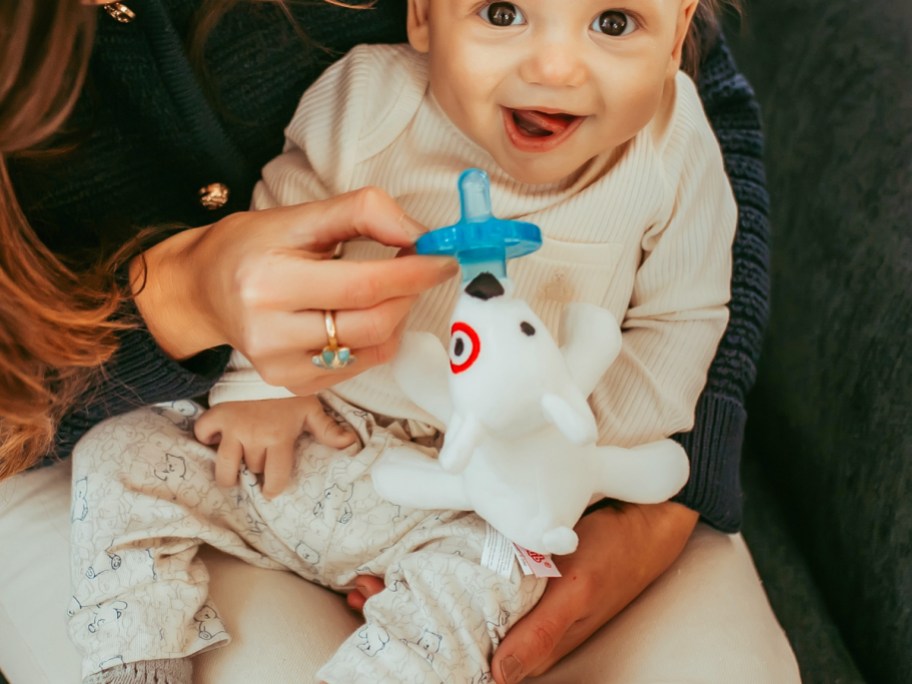 baby smiling with wubbanub pacifier nearby