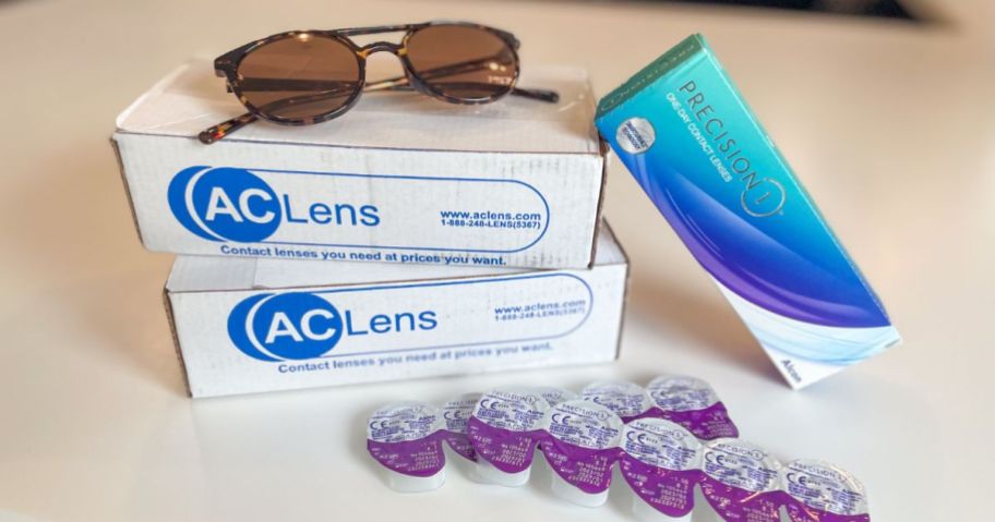 AC Lens boxes with glasses on top and contact lenses beside of them