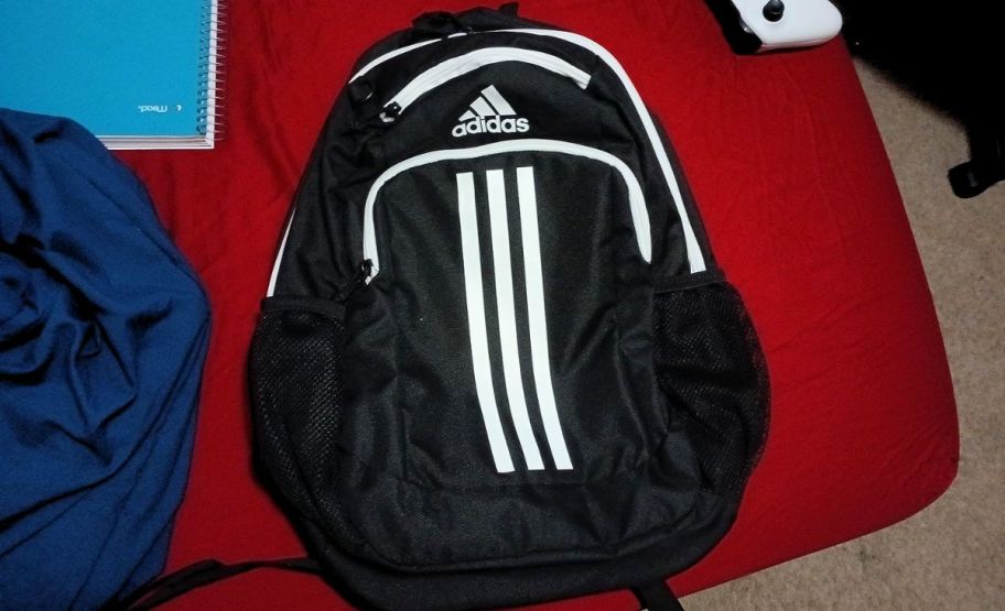 a black adidas backpack on a bed