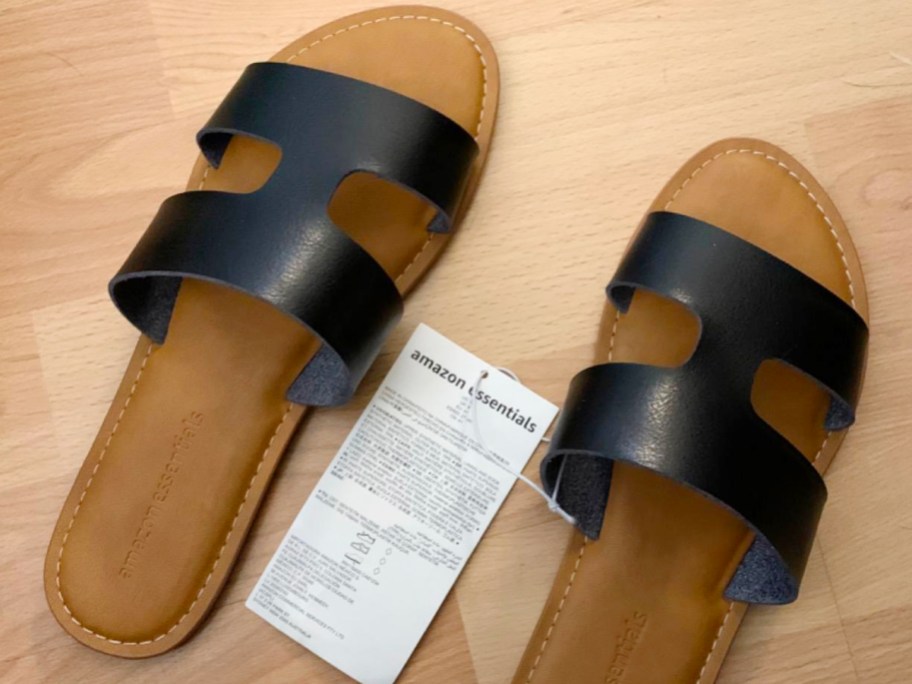 tan and black amazon essentials sandals with tag laying on floor