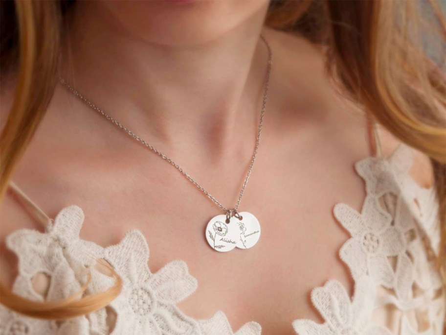 woman wearing persaonlized necklace with two discs with flowers and names