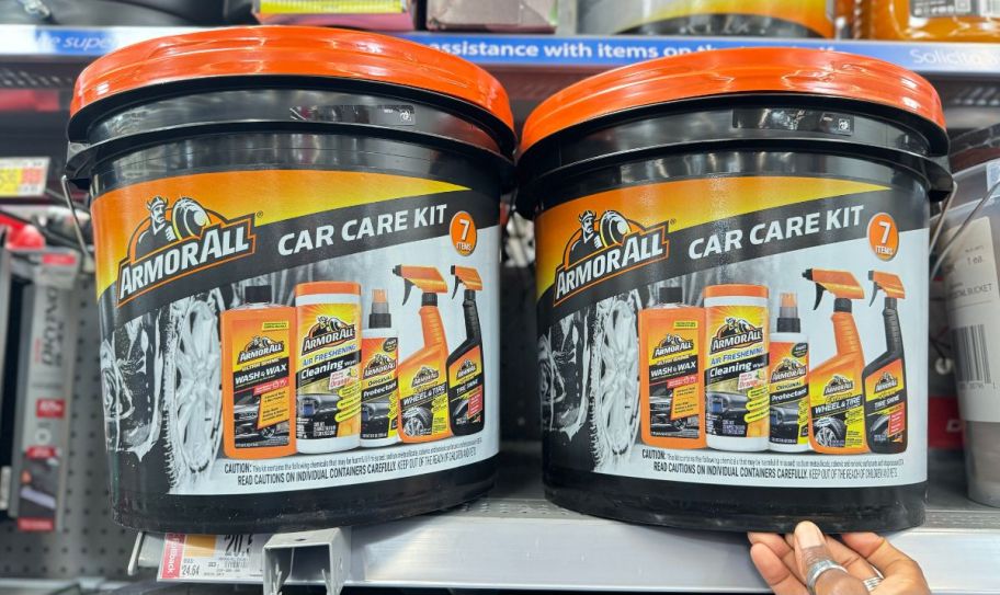 a womans hand holding the bottom edge of a bucket of car cleaning products