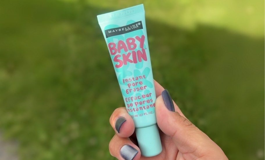 a womans hand holding a tube of pore minimizer
