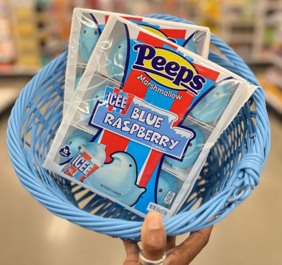 a womans hand displaying an light blue basket containing 2 packages of blue peeps