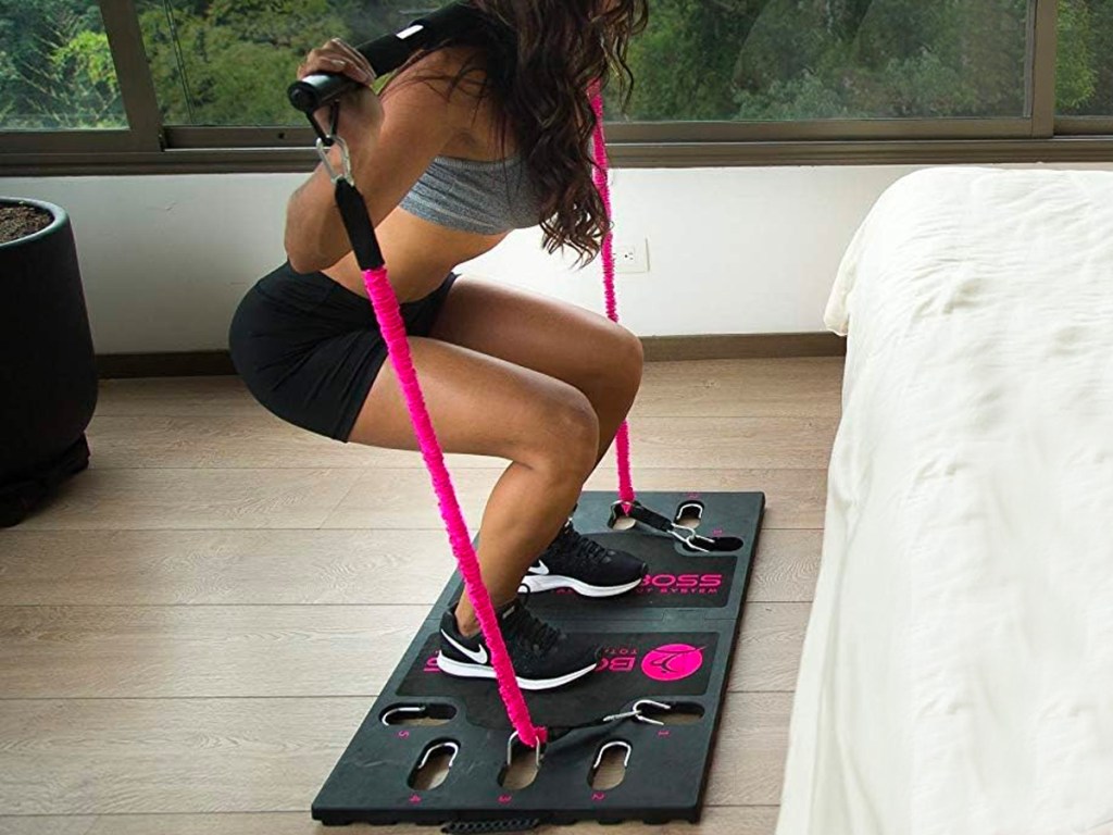 woman working out using bodyboss pink and black home gym in bedroom