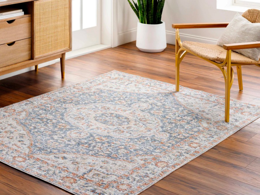 blue and pink area rug with design on hardwood floor next to wooden woven chair