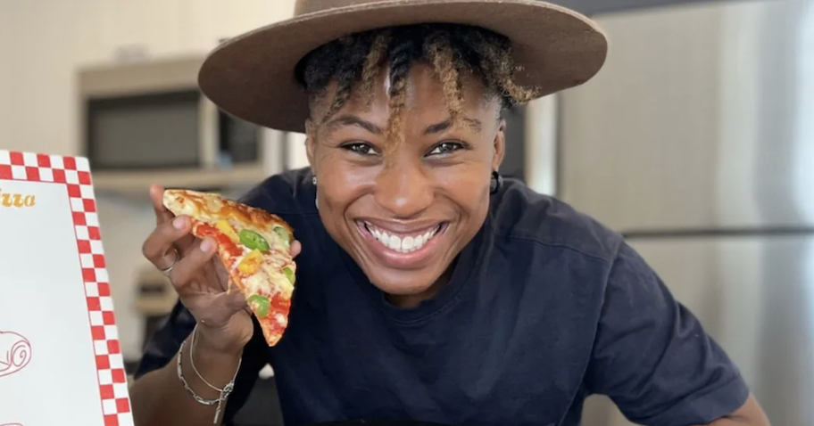 woman holding up slice of pizza with peppers