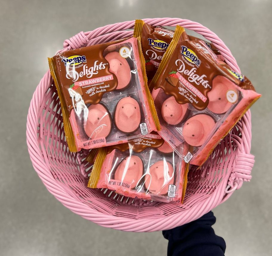a womans hand displaying a pink colored basket containing 3 packages of strawberry chocolate dipped peeps
