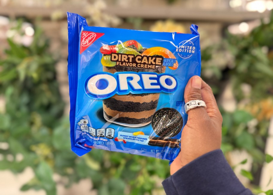hand holding up a package of limited edition dirt cake flavor oreos in front of foliage
