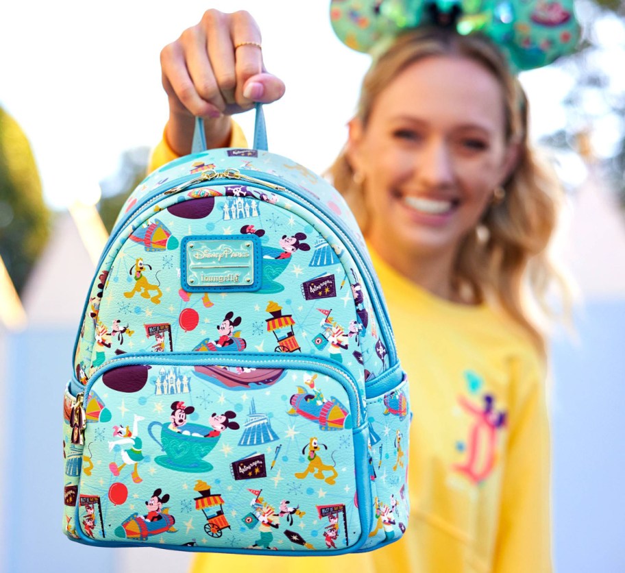 woman holding up blue mini backpack