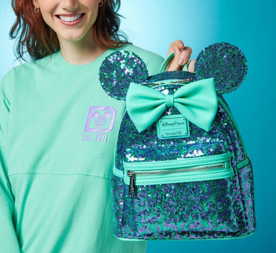 woman holding blue mini backpack with sequins and bow