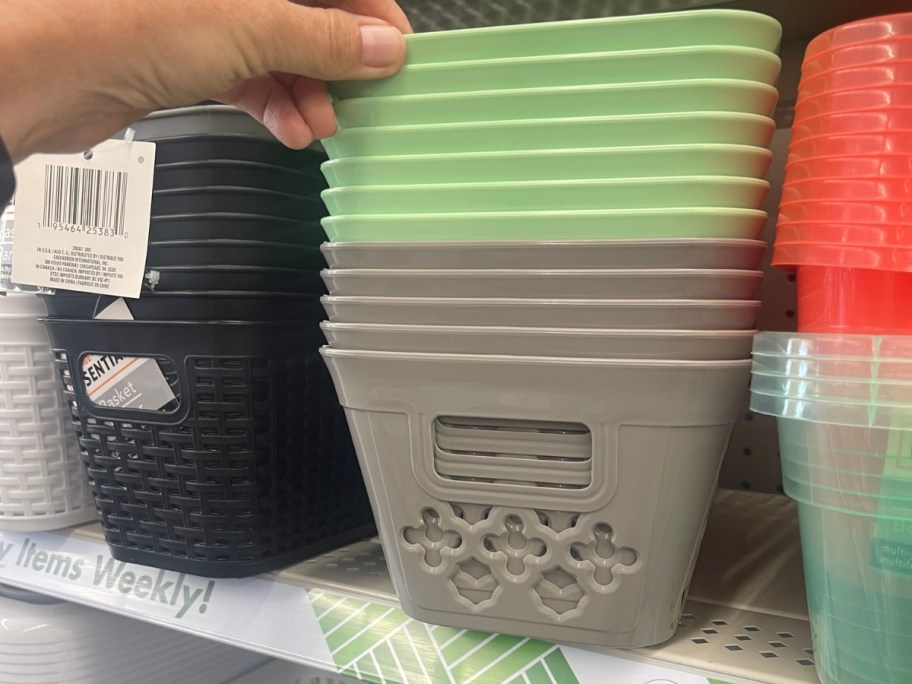 hand reaching for grey and green medium size plastic storage baskets on a shelf