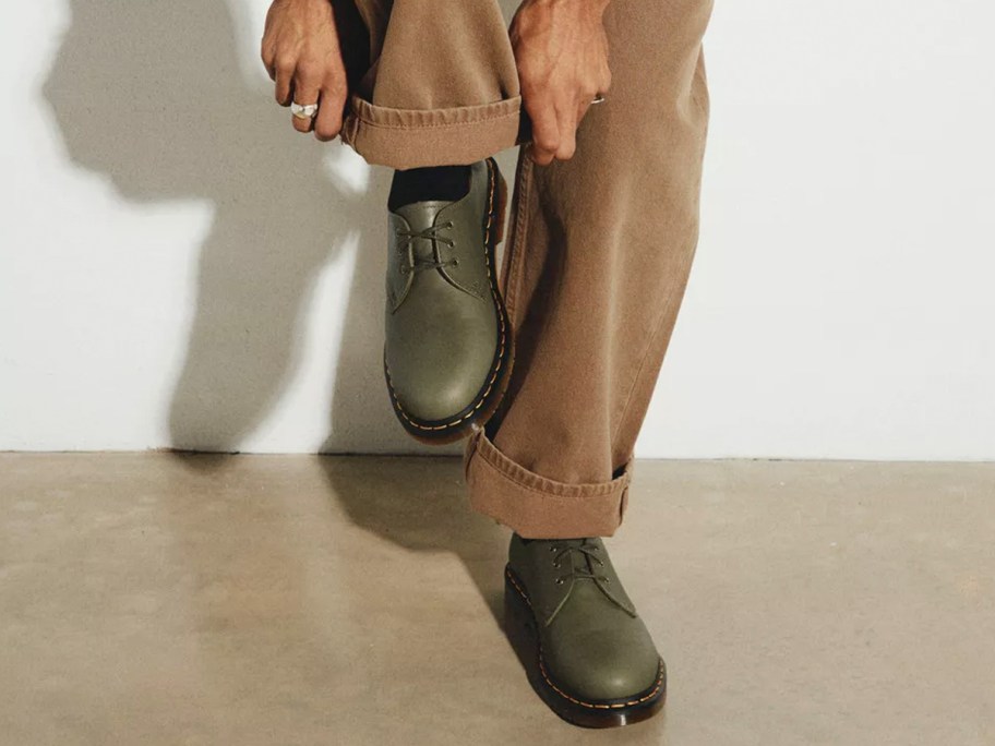 man in tan pants wearing green Dr. Martens shoes