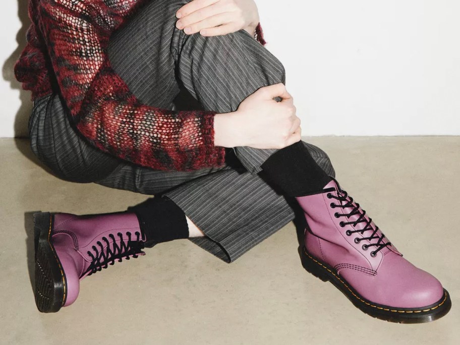 woman sitting in gray pants and pink lace up dr martens