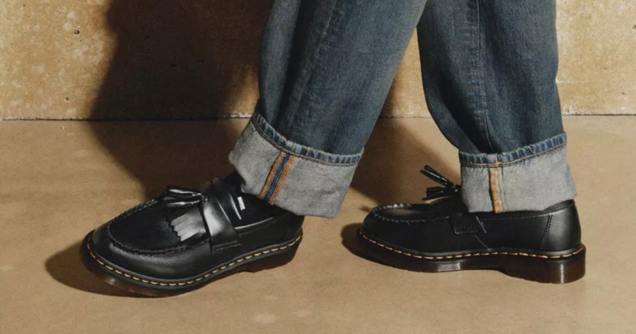 man in jeans wearing black Dr. Martens loafers 