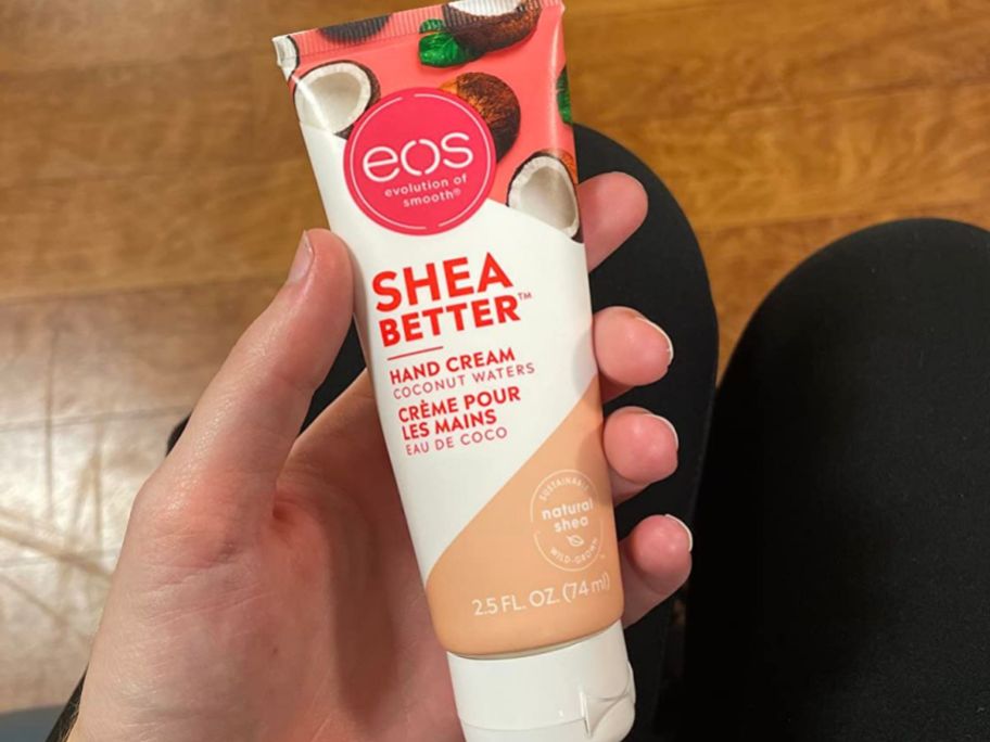 Hand holding a tube of eos Hand Cream in the coconut scent