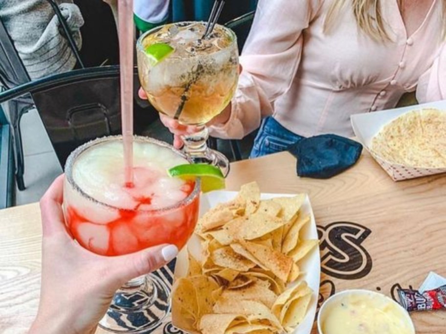 toasting with Margaritas over a plate of chips