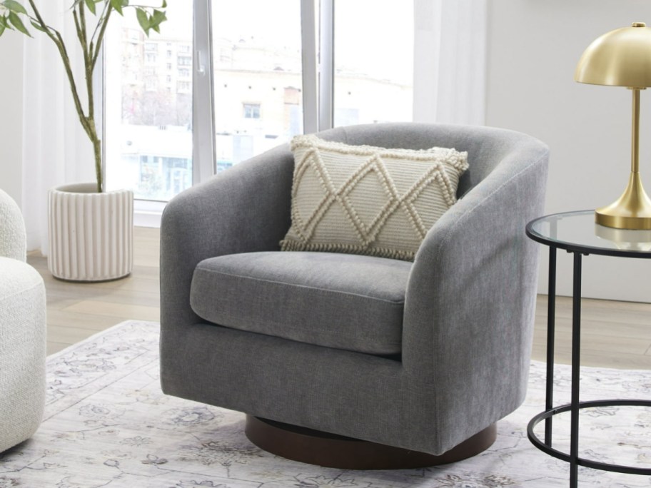 gray swivel chair with a wood base and pillow