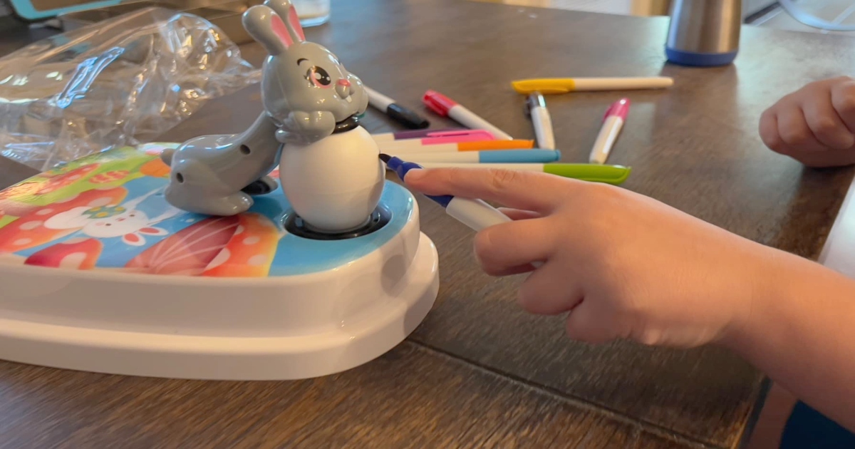 Child's hand coloring egg with bunny egg kit.