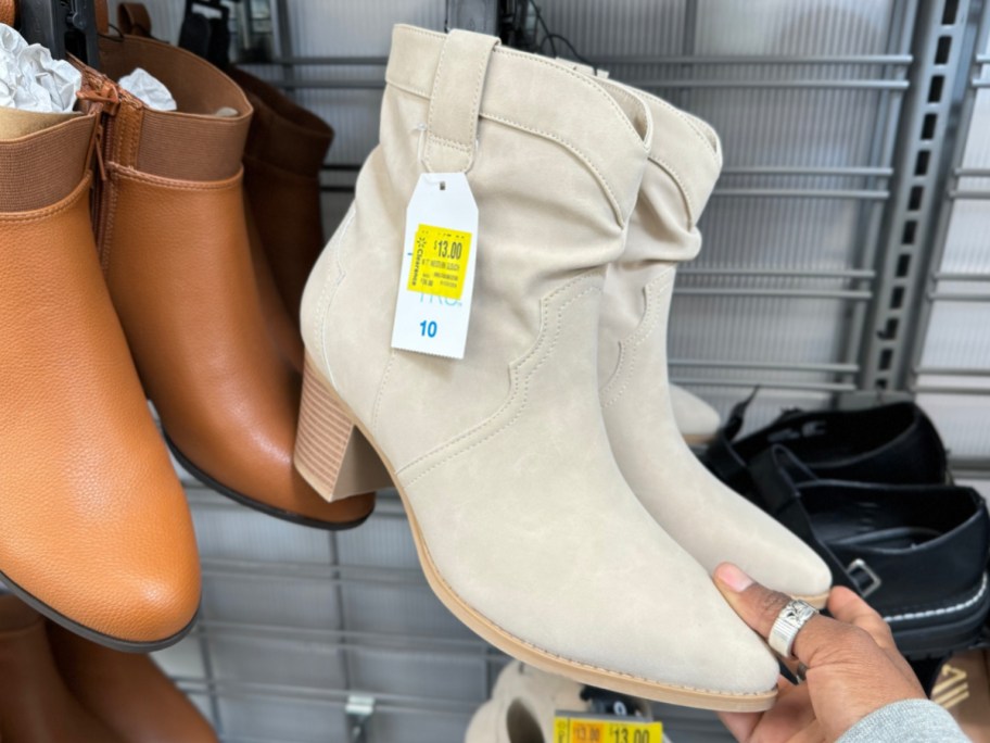hand holding Western Glouch boots in beige at the store