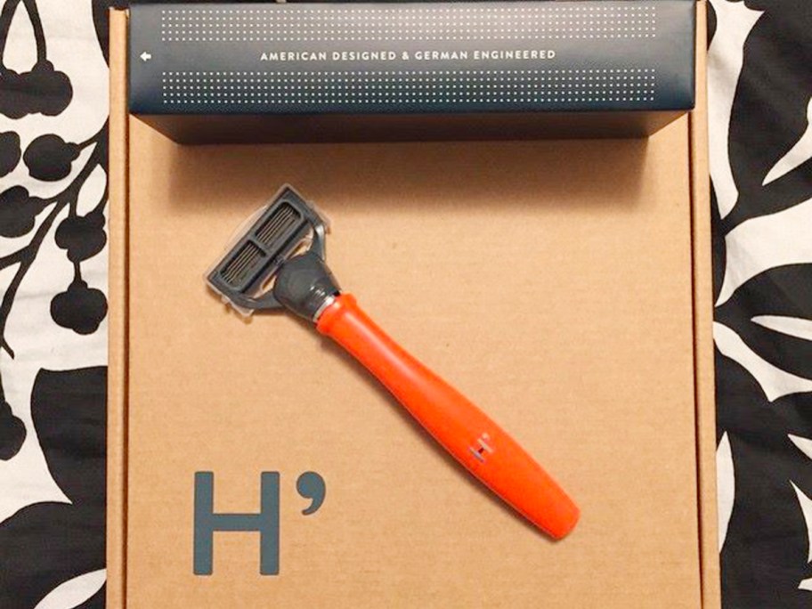 harrys orange razor handle with blade sitting on box