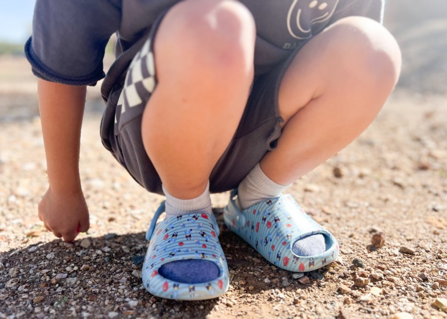 close up of kid wearing bluey crocs in dirt