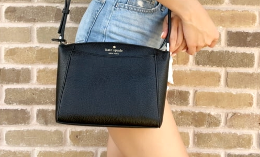 young woman wearing a black kate spade purse, one of the retailers that offer college student discounts