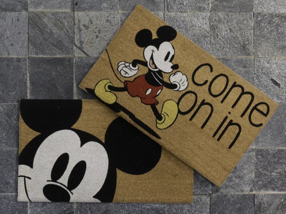 2 coir doormats with Mickey Mouse on them laying on a stone floor