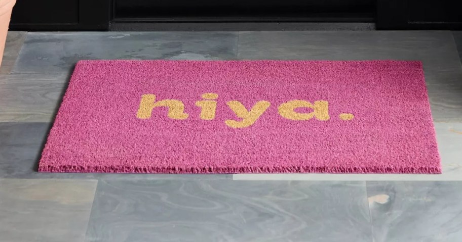 pink coir doormat that says "hiya" in front of door