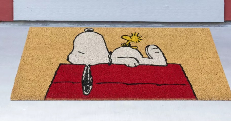 coir doormat in front of a door with Snoopy & Woodstock napping on Snoopy's red doghouse