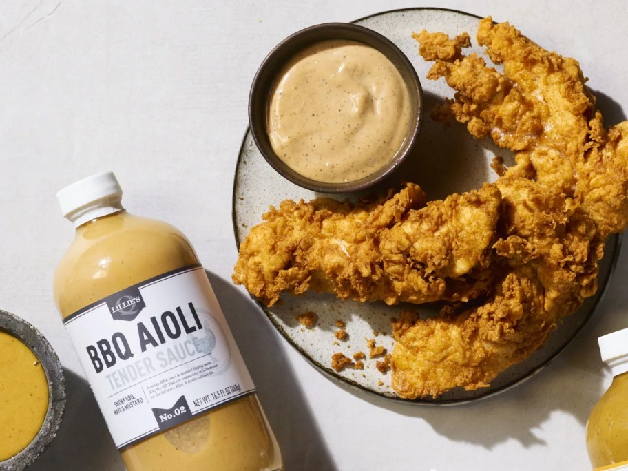 bottle of gold BBQ sauce next to plate of chicken tenders