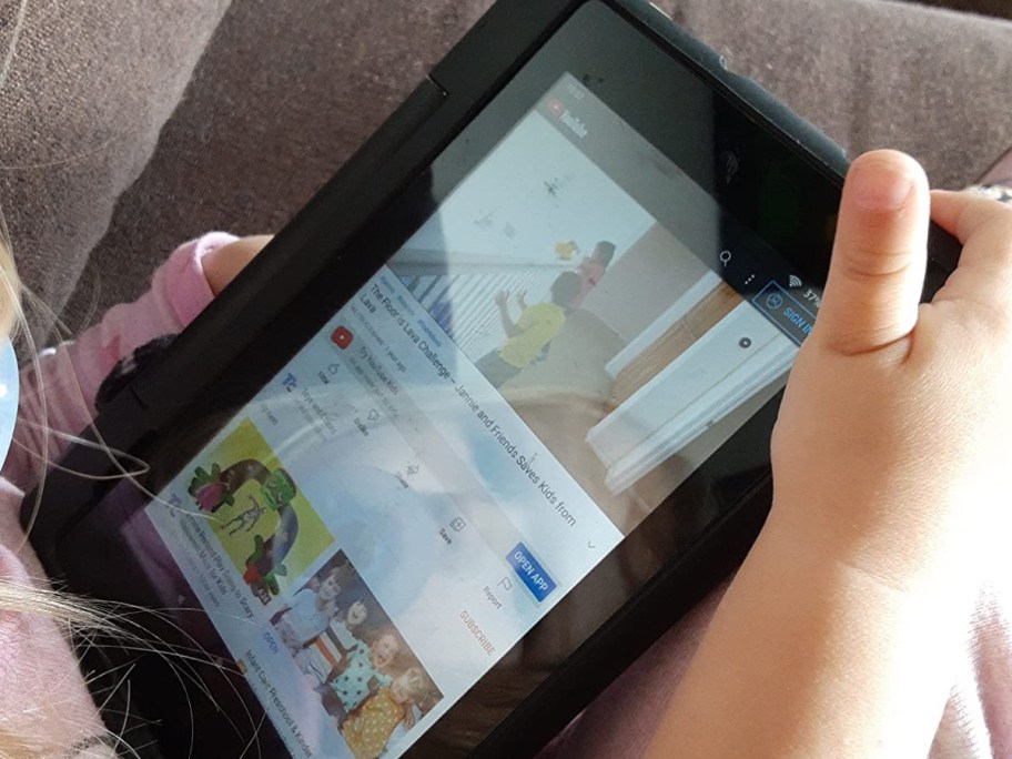 little girl holding black tablet in hand