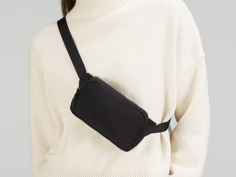 woman in white sweater with black mini belt bag across her chest